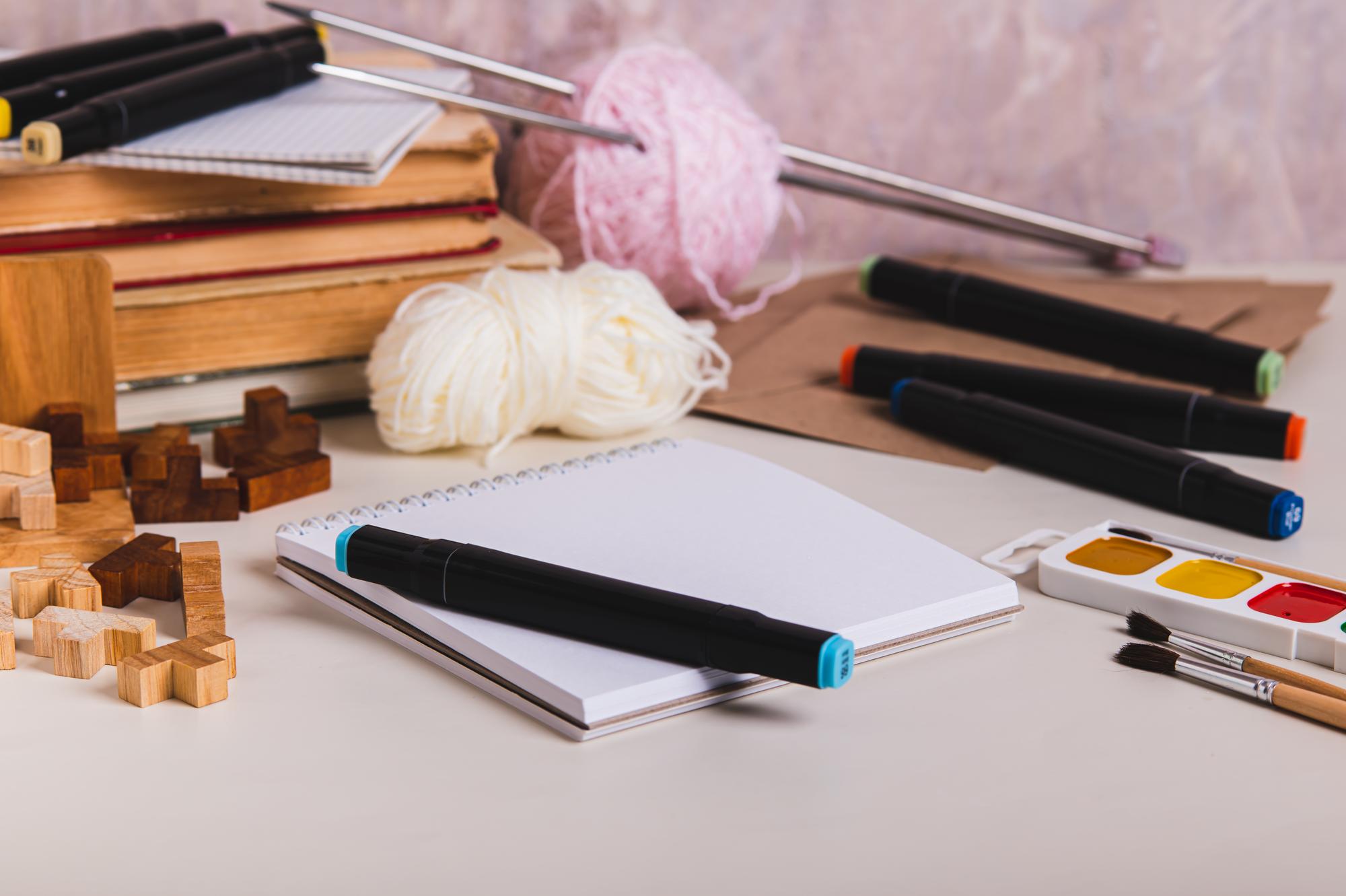 Workspace with embroidery tools and sketchbook